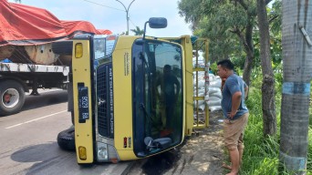 Dihantam Bus, Truk Bermuatan Biji Plastik Terguling di Jalan Nasional Lamongan